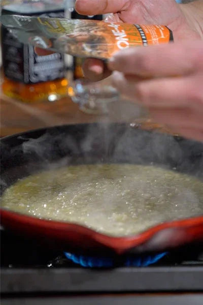 Seasoning being sprinkled into sizzling skillet on stovetop, perfect for BBQ rubs and all-natural cooking.