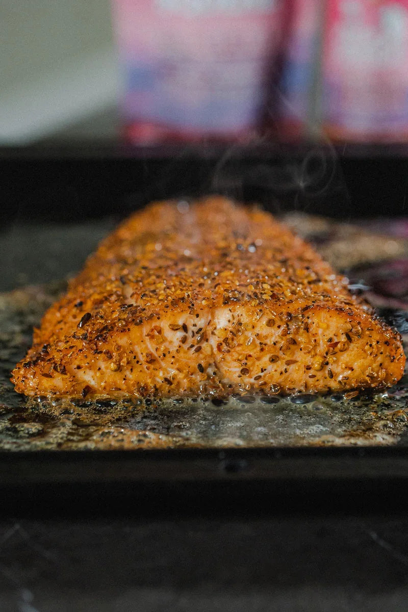 Seasoned salmon sizzling on grill with aromatic spice rub, perfect for BBQ meals